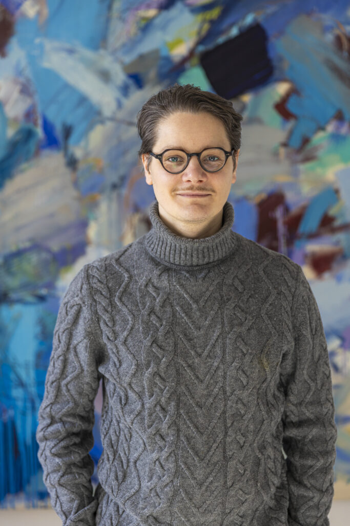 weißer Mann mit Brille und grauem Pullover