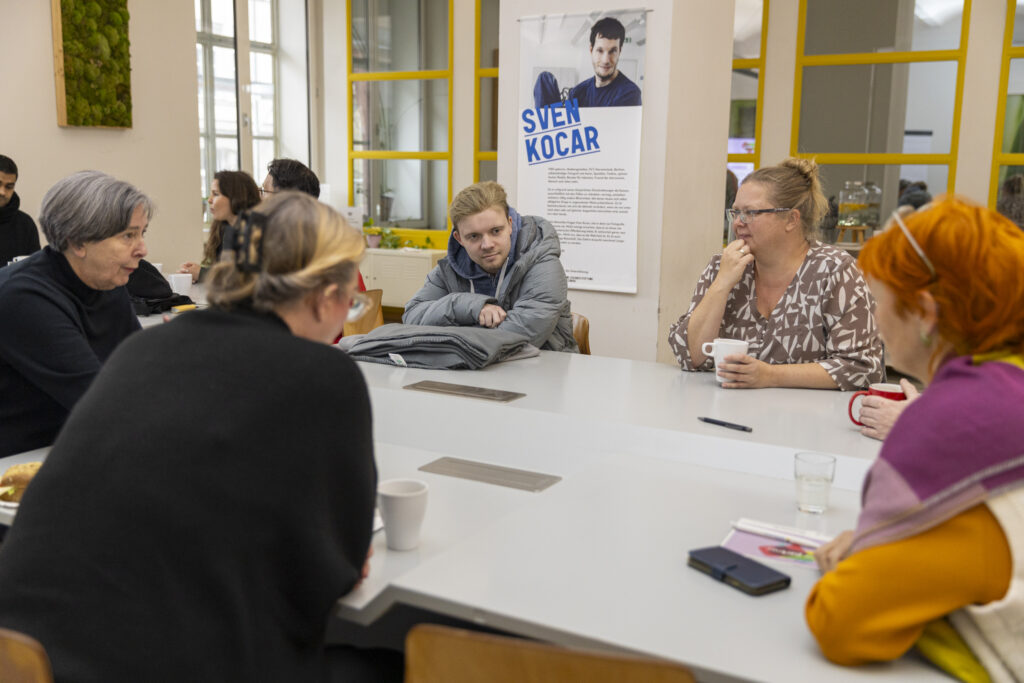5 Personen an einem Tisch im Gespräch bei der ersten Abschlussveranstaltung von be partner.